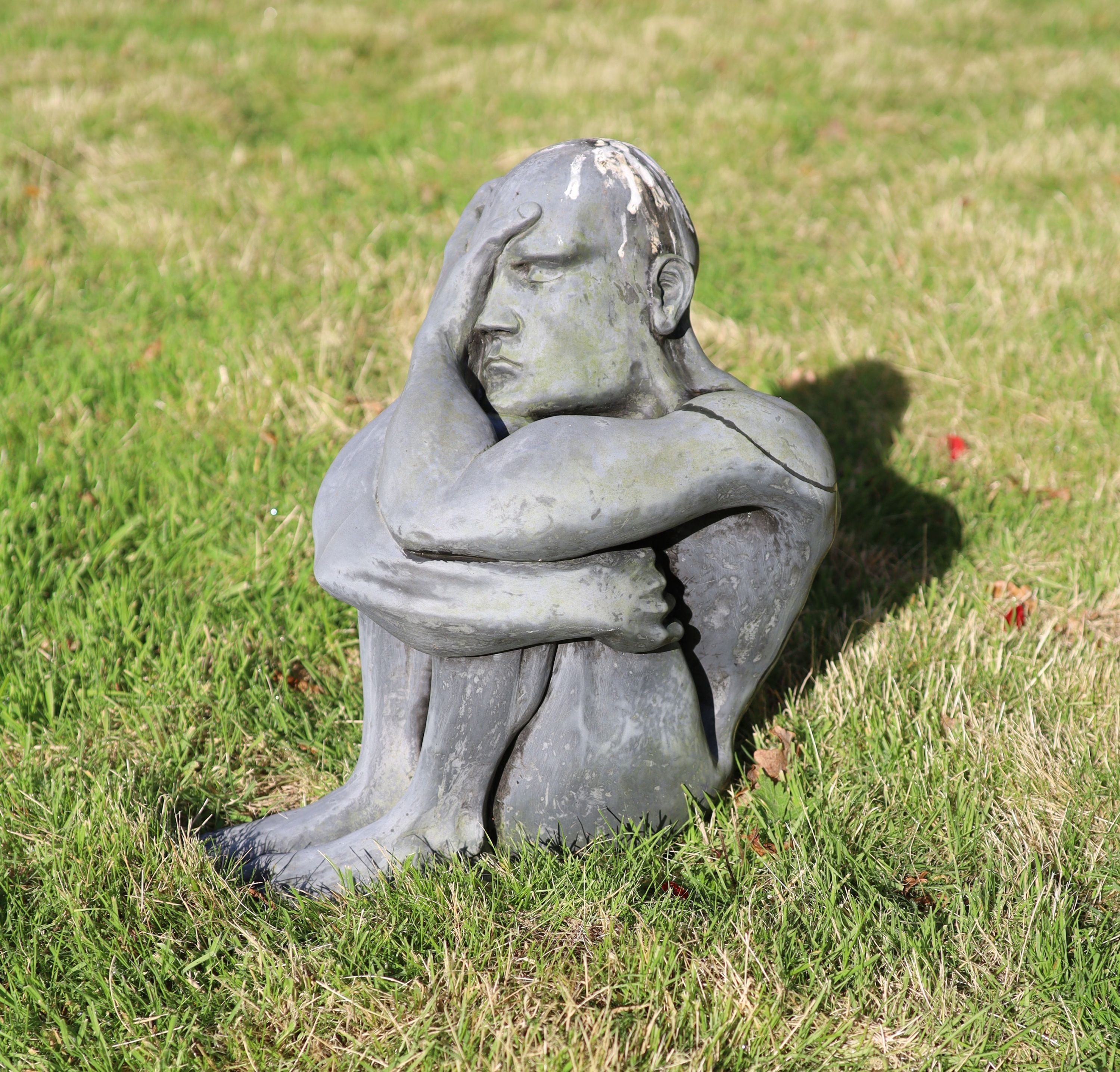 A simulated lead resin garden statue of a seated man, height 49cm, with a damaged marble pedestal, height 78cm